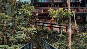 Un edificio tradizionale a più piani con un balcone in legno e una scala immersa nel verde.