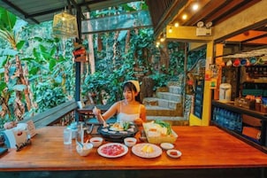 Un restaurante con una mesa de madera, varios platos y una persona comiendo.