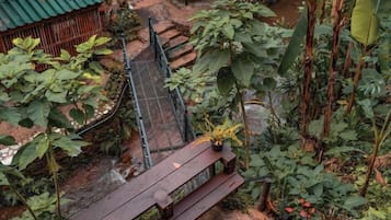 Een tuin met een houten bankje, een kleine brug en verschillende planten.