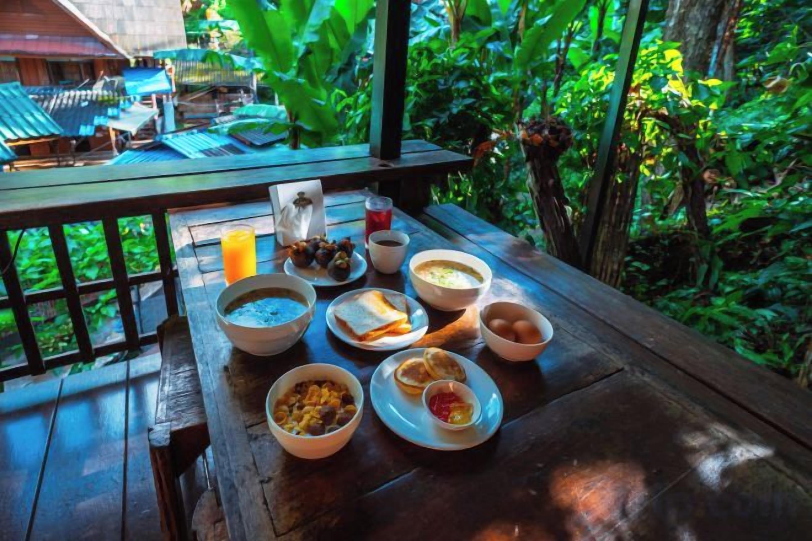 A wooden table with breakfast items and a view of a lush garden.