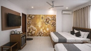 Una habitación de hotel con cama, televisor, mesa de centro y pared decorada con un mural floral.