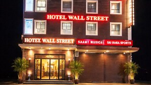 Un hotel de varios pisos con señalización iluminada que dice "HOTEL WALL STREET" y "HOTELY WALL STREET".