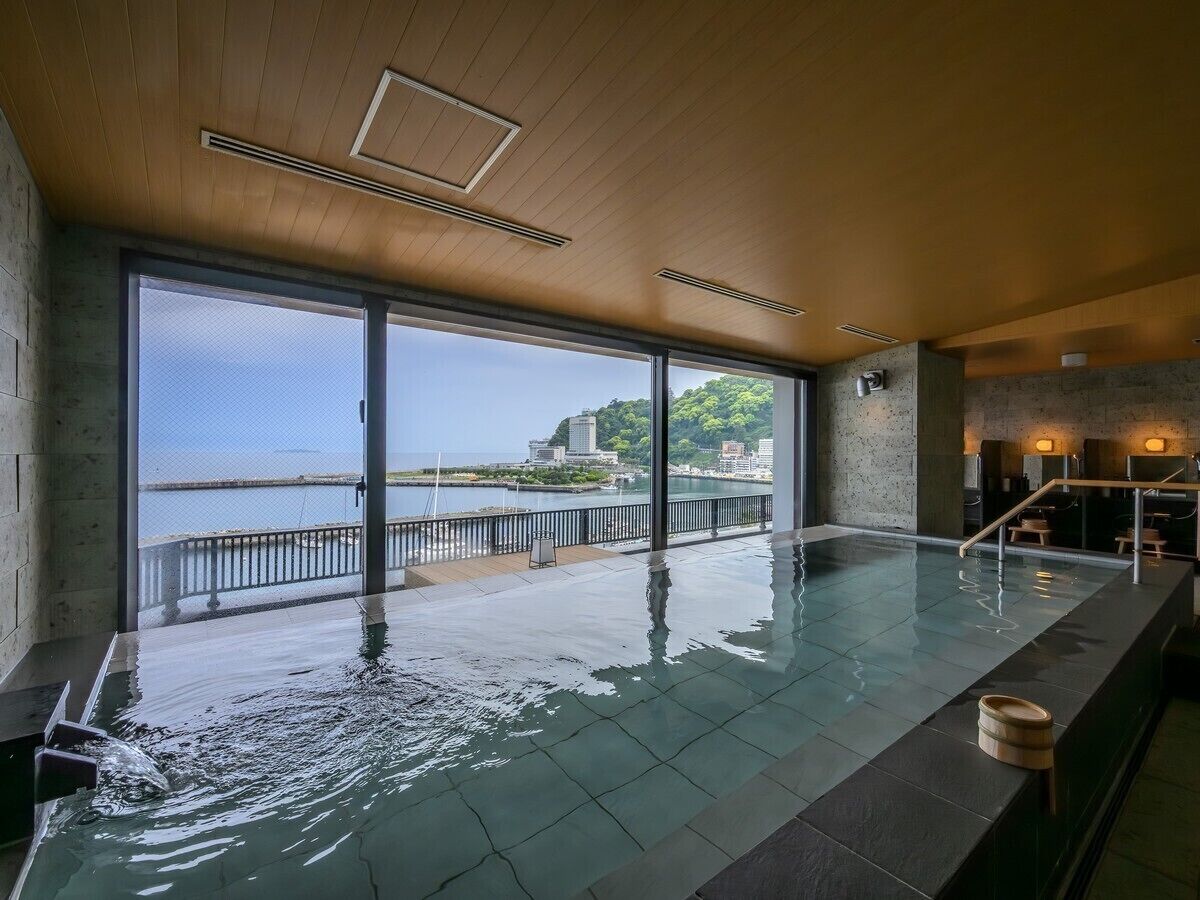 An indoor swimming pool with a view of a body of water and buildings.