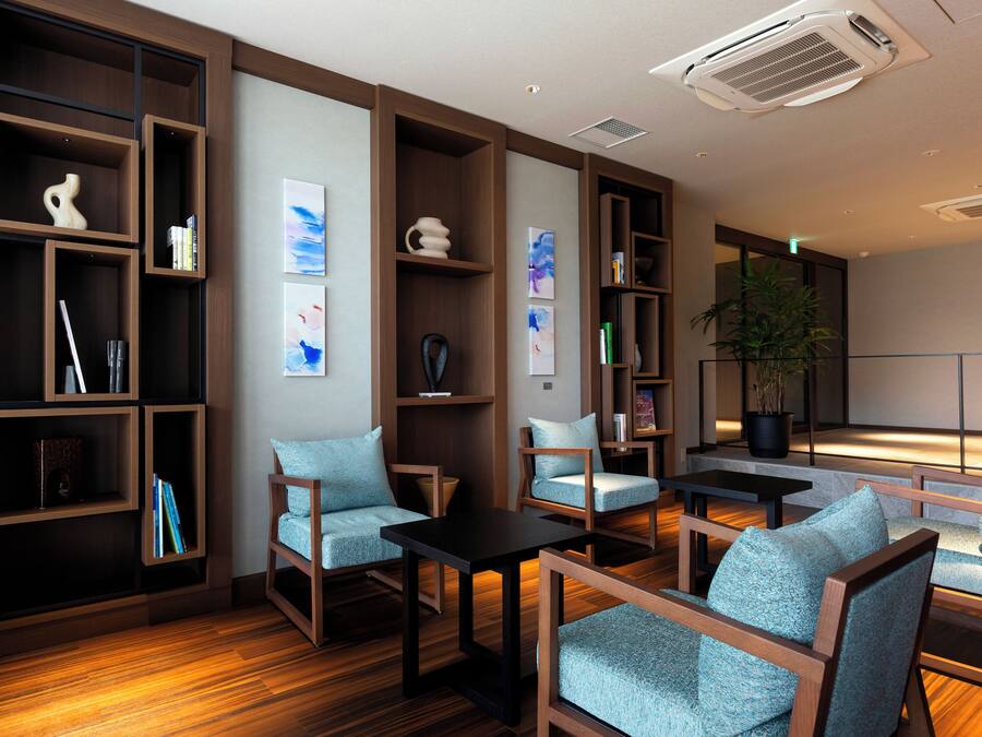 A modern lounge area with wooden furniture, bookshelves, and artwork.