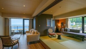 A modern hotel room with a balcony, a sofa, a chair, and a dining area. - Atami Hotel Nagisakan (Atami)