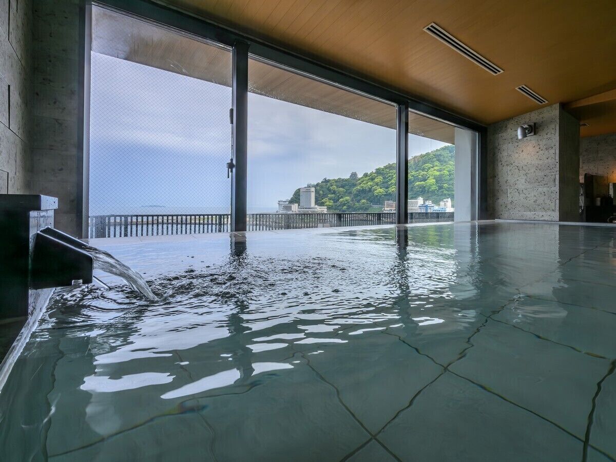 Una piscina interior con vistas a un paisaje urbano y colinas.