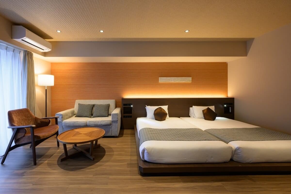 Una habitación de hotel moderna con una cama grande, un sofá, una silla y una mesita.