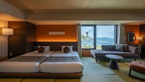 Camera d'albergo con un letto grande, un divano, un tavolino e vista sul mare.