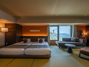 A hotel room with a large bed, a sofa, a small table, and a view of the sea. - Atami Hotel Nagisakan (Atami)
