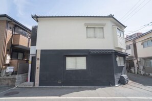 A two-story residential building with a black and white facade, a small window on the upper floor, and a visible garage door. - New open！Sunflower 5-minute walk from Nishi-Kujo Station (Osaka)