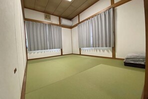 Quarto com piso de tatame, portas corrediças e cama estilo futon.