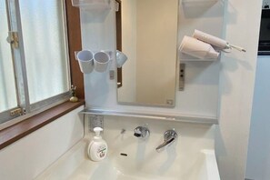 A bathroom with a sink, mirror, and storage shelves. - KaiTen house Jasmine (Beppu)
