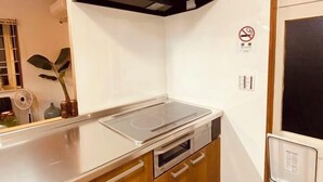 A kitchen with a built-in stove, oven, and microwave. There is a no-smoking sign on the wall. - KaiTen house Jasmine (Beppu)
