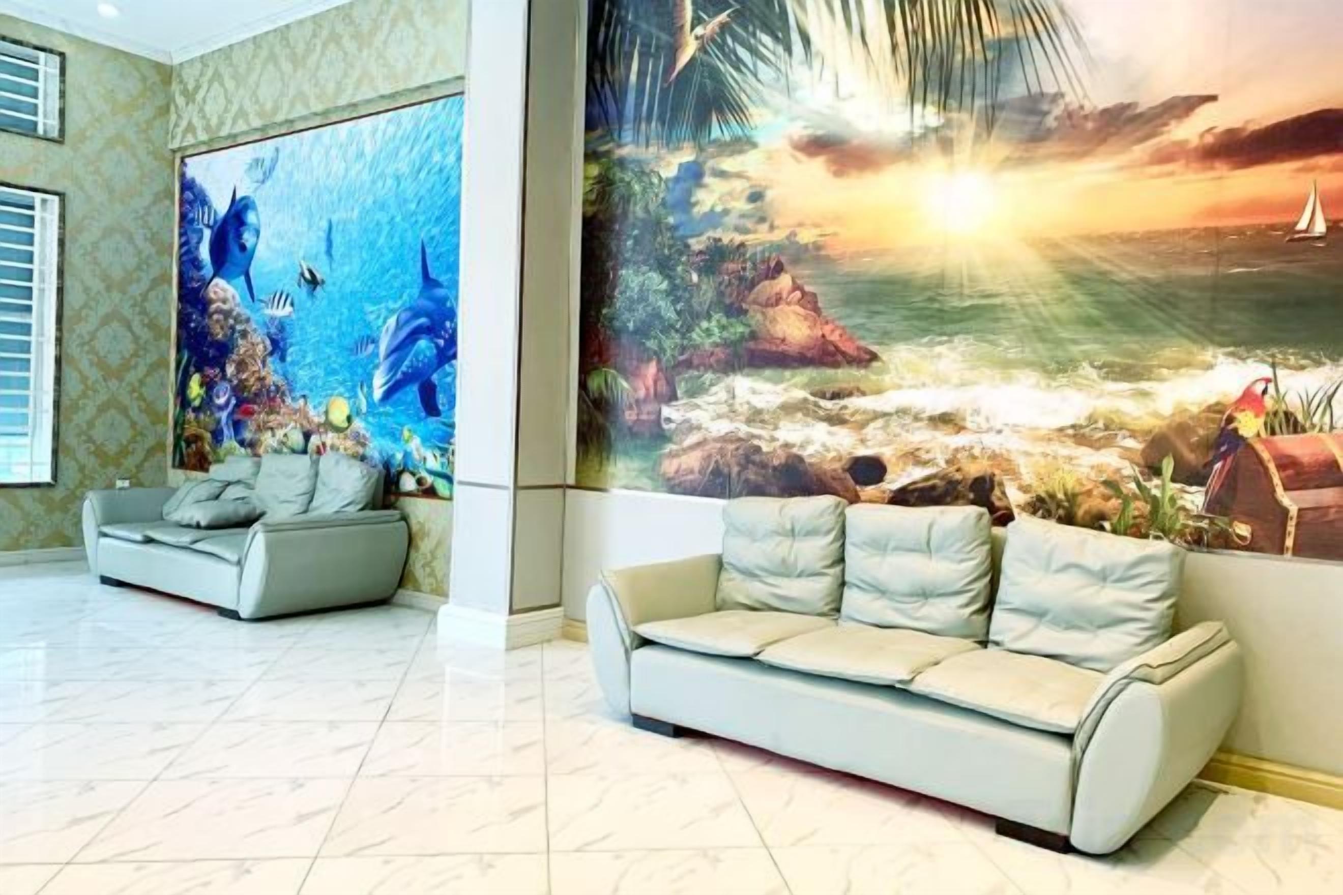 A lobby with a large mural of a sunset over the ocean, a sofa, and a patterned wall.