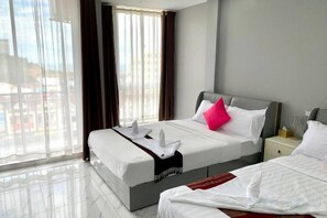 A hotel room with a large bed, a bedside table, and a view of the city. - Sok Eng Hotel (Sihanoukville)