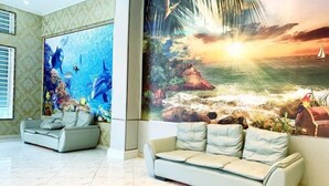 Amplia sala de estar con un gran mural de una escena submarina y una playa al atardecer. Hay dos sofás y una mesa de centro.