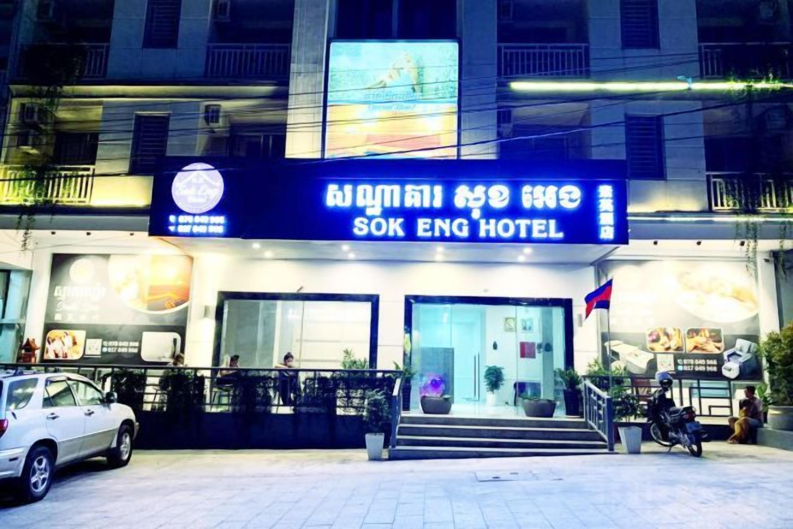 Het uiterlijk van Sok Eng Hotel, met een opvallend bord, een trap naar de ingang en een vlag.