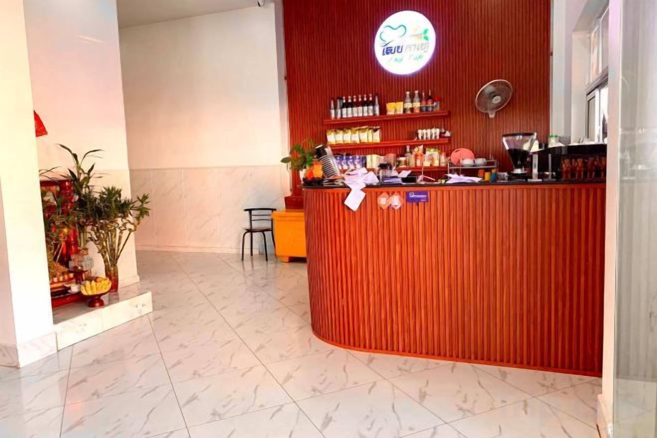 A reception area with a red counter, a sign with a logo, and a plant.