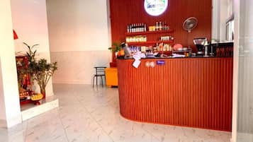 A reception area with a red counter, a sign with a logo, and a plant.