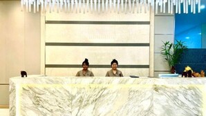 Un mostrador de recepción con encimera de mármol y dos empleados sentados detrás.