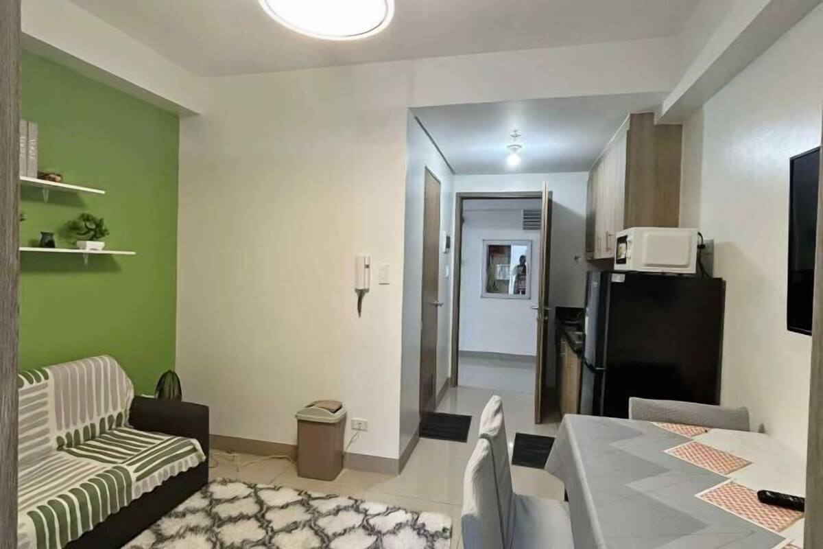 Espai vital compacte amb un sofà, taula de dinar i un cubell de brossa.