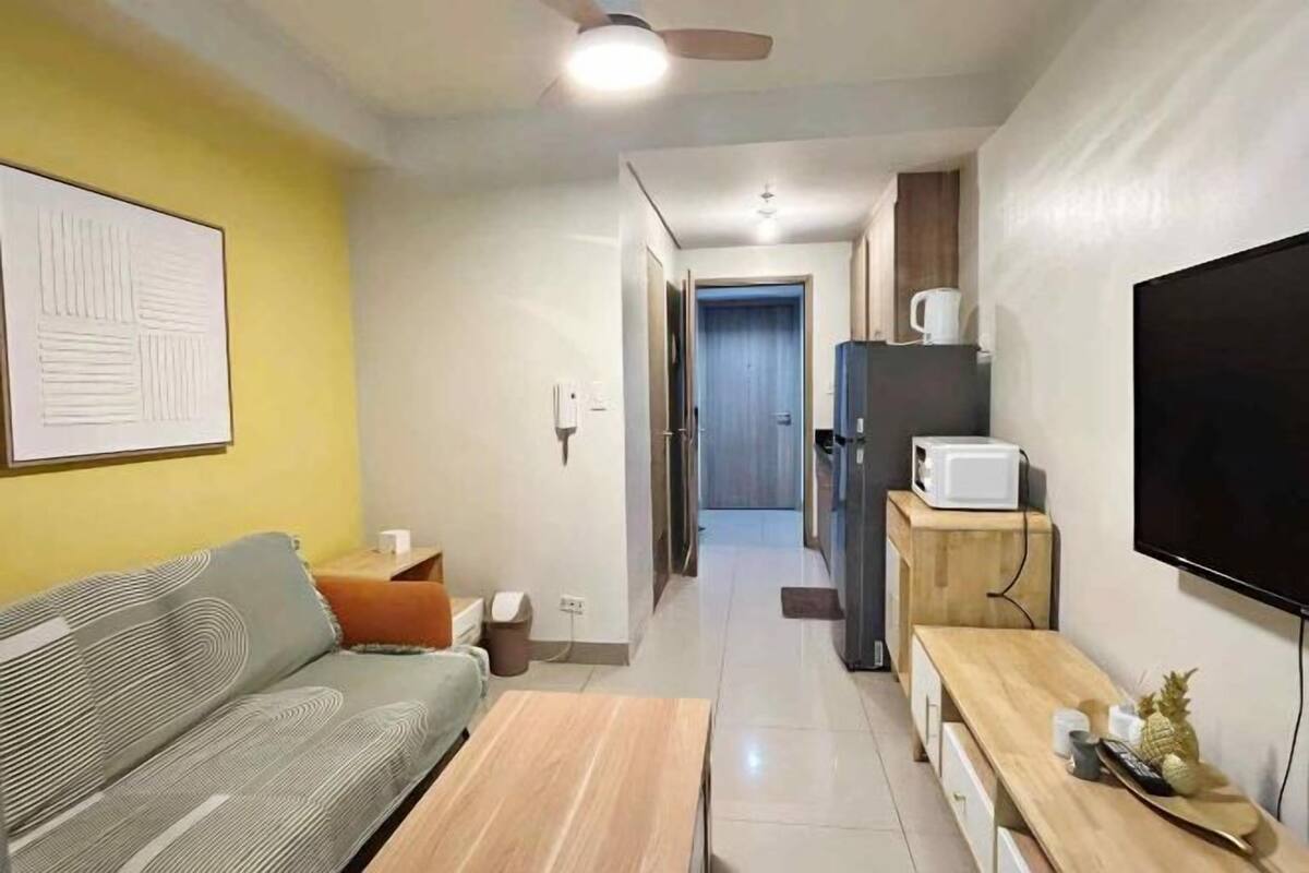 Un saló modern amb sofà, taula de centre, televisió i zona de cuina amb microones.