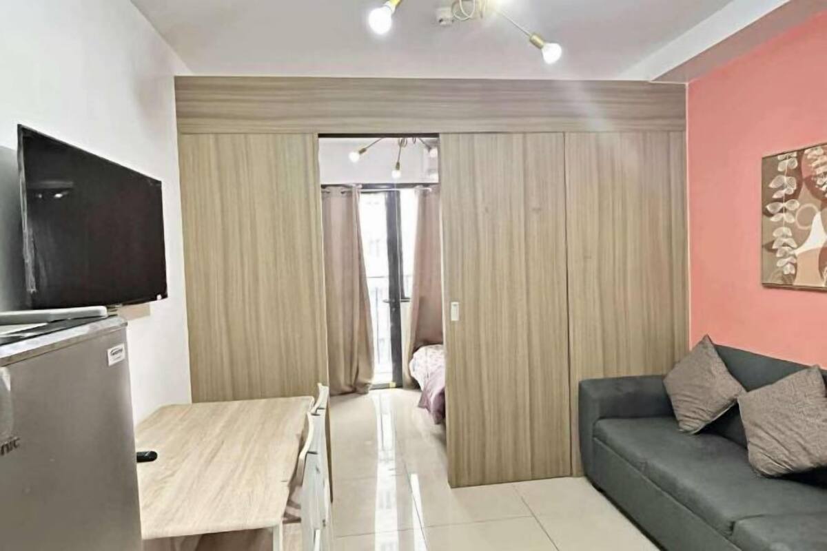 Habitació amb llit, televisió, escriptori, sofà i porta que dóna a una altra habitació.