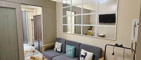 A modern living room with a grey sofa, a flat-screen TV mounted on a wall, and a wooden coffee table.