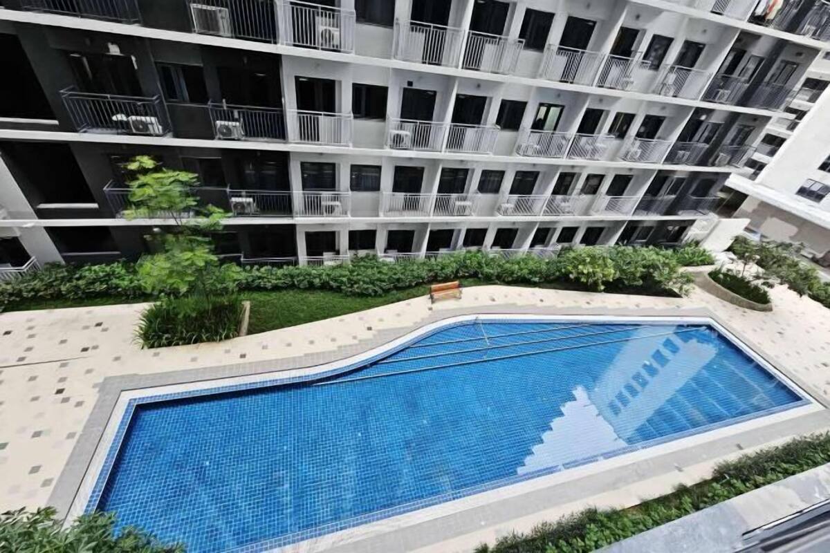 Edifici modern amb piscina envoltada de vegetació.