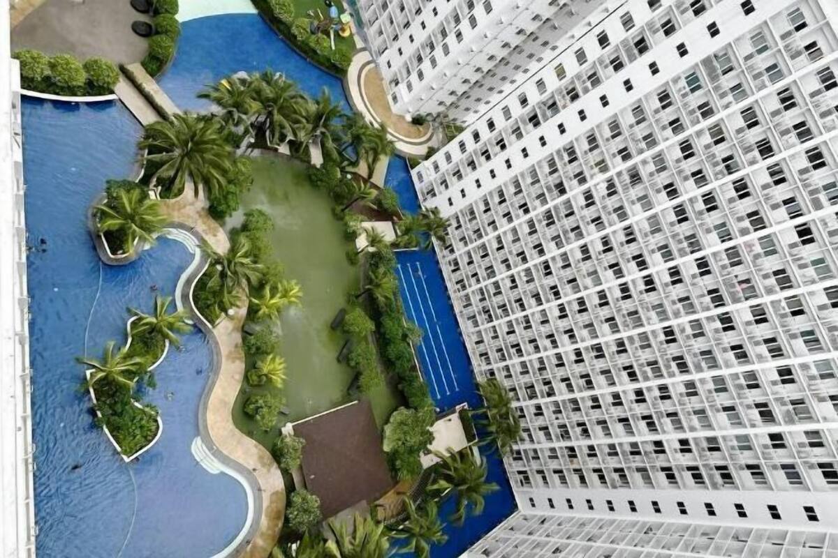 Un edifici de grans alçades amb piscina, palmeres i un camí sinuós.