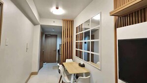 A compact room with a dining area, a large window, and a TV. - MOA getaway staycations (Pasay)