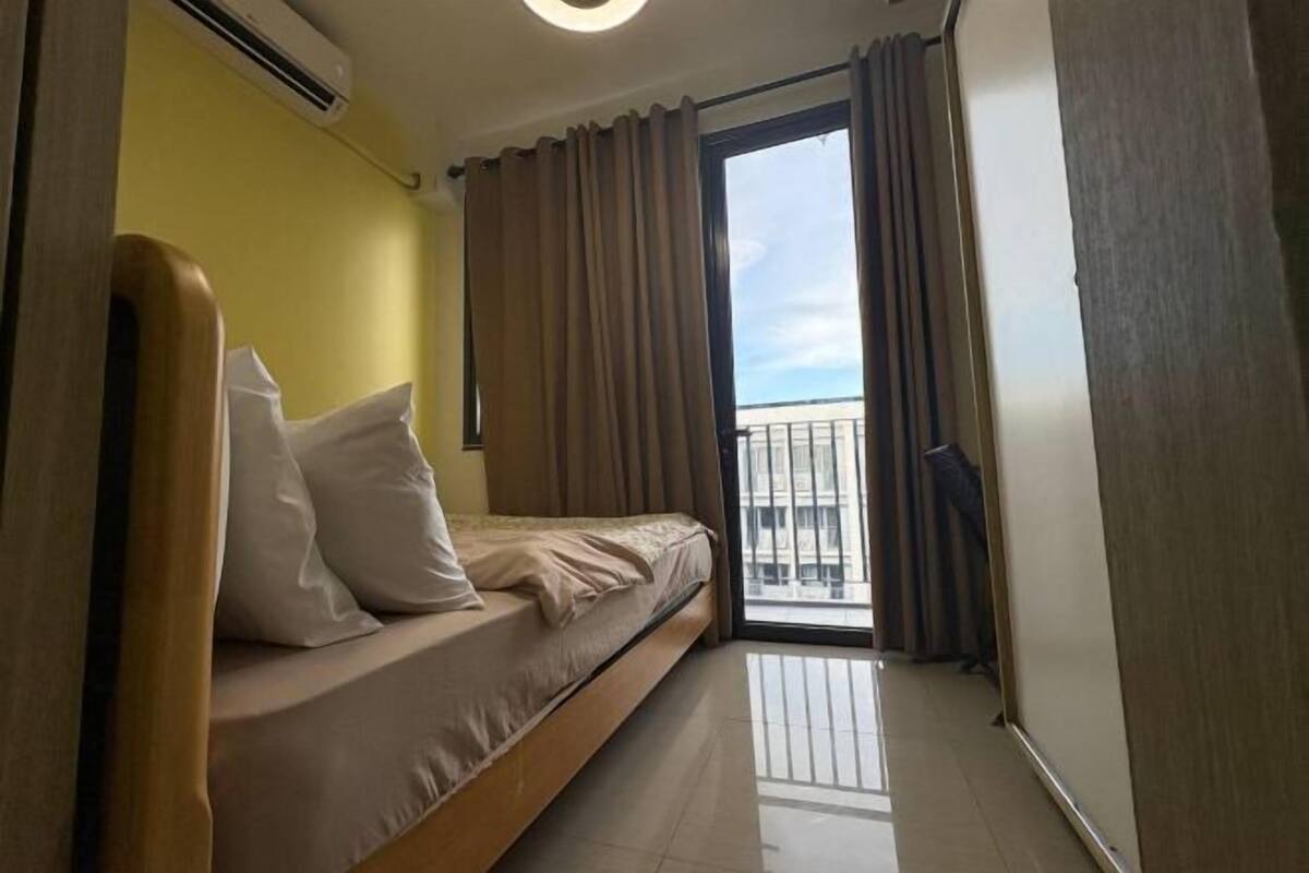 Un dormitori amb un llit, cortines i vista exterior.