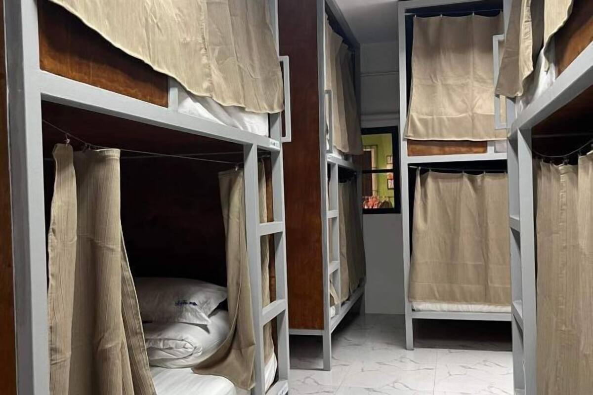 Ein Schlafsaalzimmer mit Etagenbetten, jeweils mit einem Vorhang.