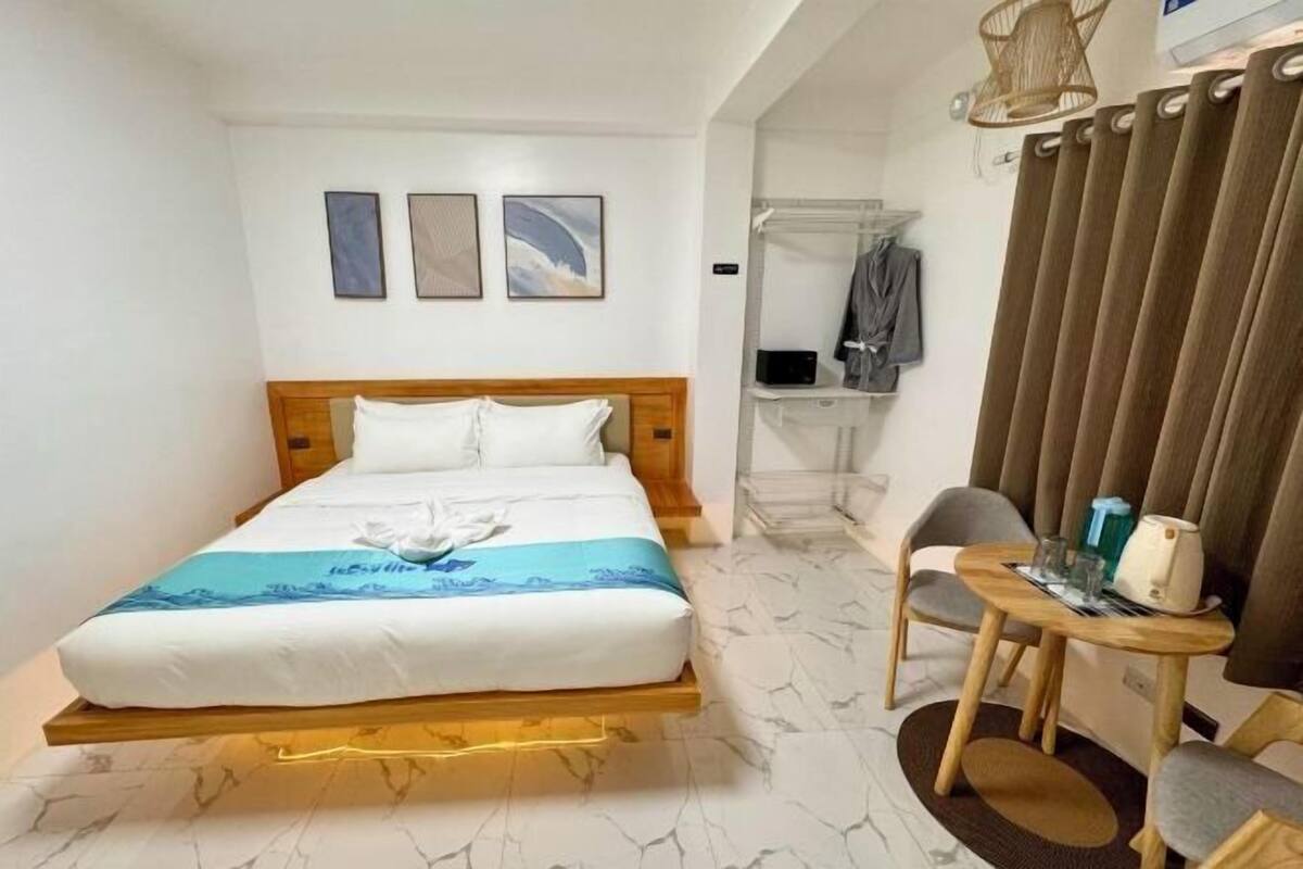 Ein Hotelzimmer mit einem Bett, einem kleinen Tisch mit Stuhl, einem Bademantel und einer Duschkabine.