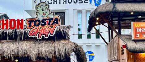 A restaurant named 'Tosta Chon' with a thatched roof and a sign featuring a cartoon character.
