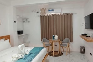 Une chambre dâhĂŽtel Ă©quipĂ©e dâun lit, dâun bureau, dâune chaise, dâune tĂ©lĂ©vision et dâune fenĂȘtre avec des rideaux.