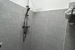 A shower with a handheld showerhead and a towel rack.