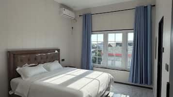 A bedroom with a bed, a window, and curtains.