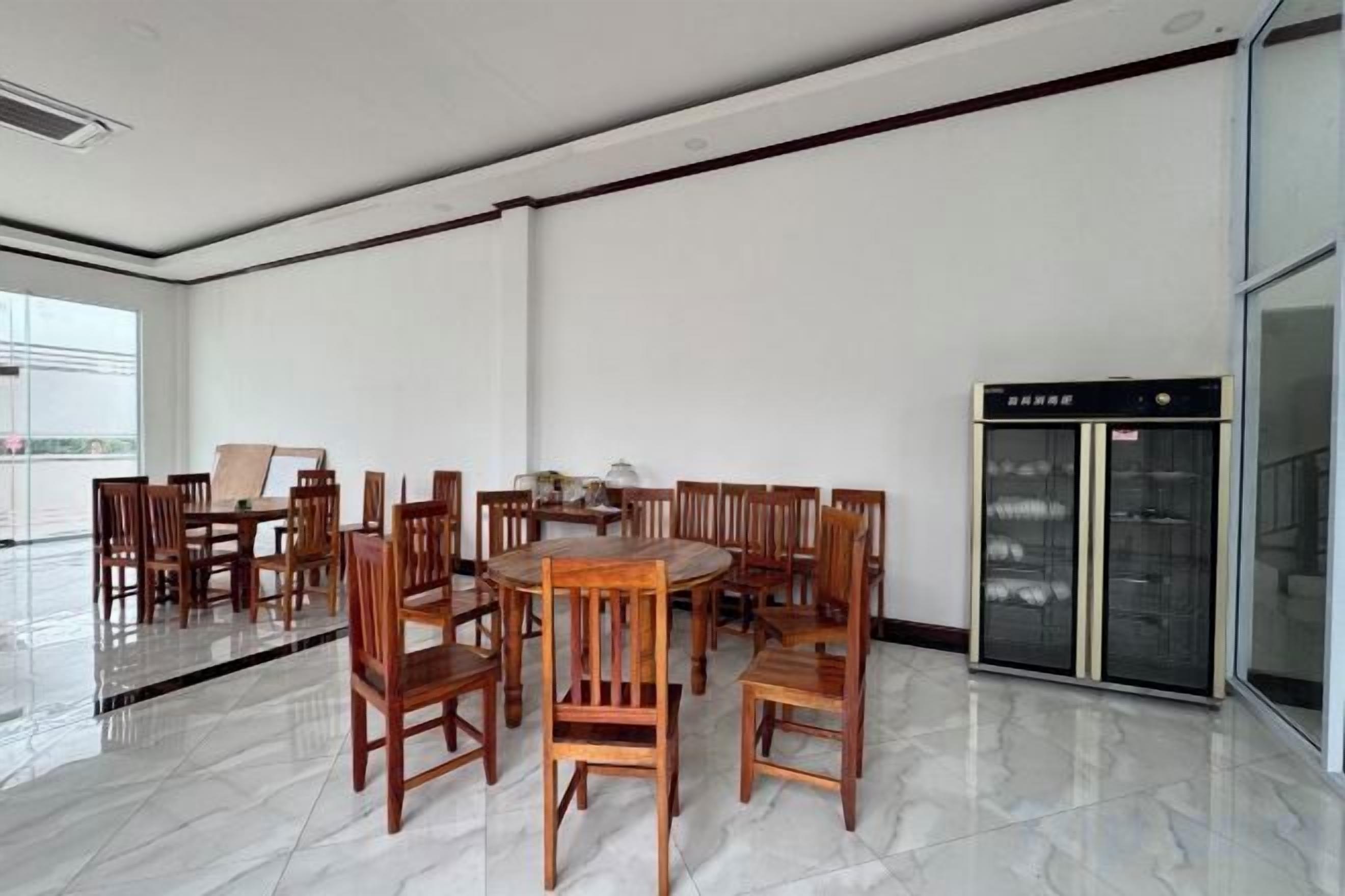 A spacious room with a large round table surrounded by chairs, a glass elevator, and a view of the outdoors.