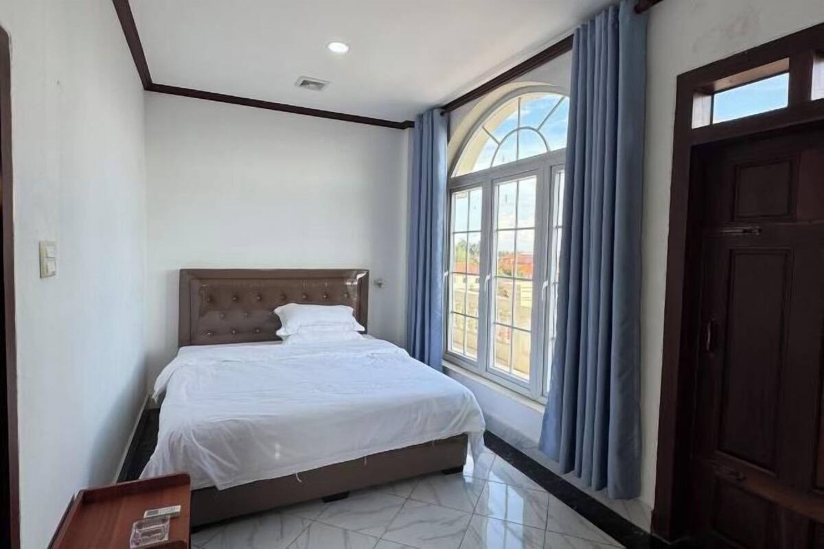 Une chambre à coucher avec un lit, une fenêtre avec des rideaux et une porte.