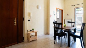 Una stanza con una porta in legno, un piccolo tavolo di legno con una pianta e un'area pranzo con quattro sedie e un tavolo.