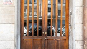 Une porte en bois, munie d’une barre de sécurité en métal, intégrée à un bâtiment en pierre.