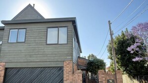 Uma casa de dois andares com garagem, com número 227, e fundação de tijolos.