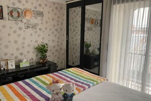 Quarto com colcha listrada, espelho, planta em vaso e cômoda.