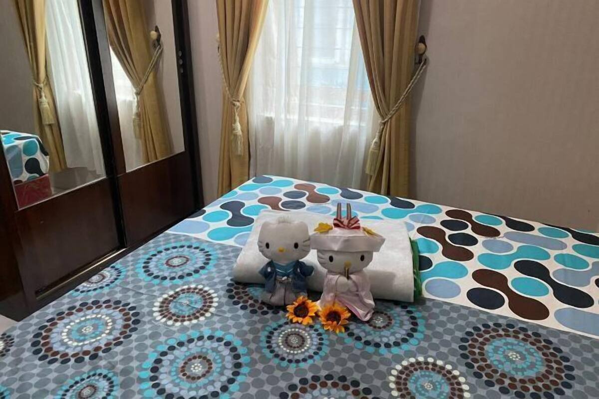 Une chambre d’hôtel avec un lit, un miroir, des rideaux et une couvre-lit à motifs.
