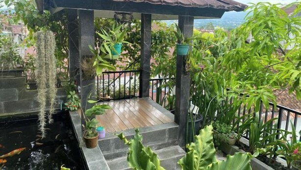 A gazebo with a tiled floor, surrounded by potted plants and a small pond with fish. - MOZA HOUSE Wonosobo (Wonosobo)