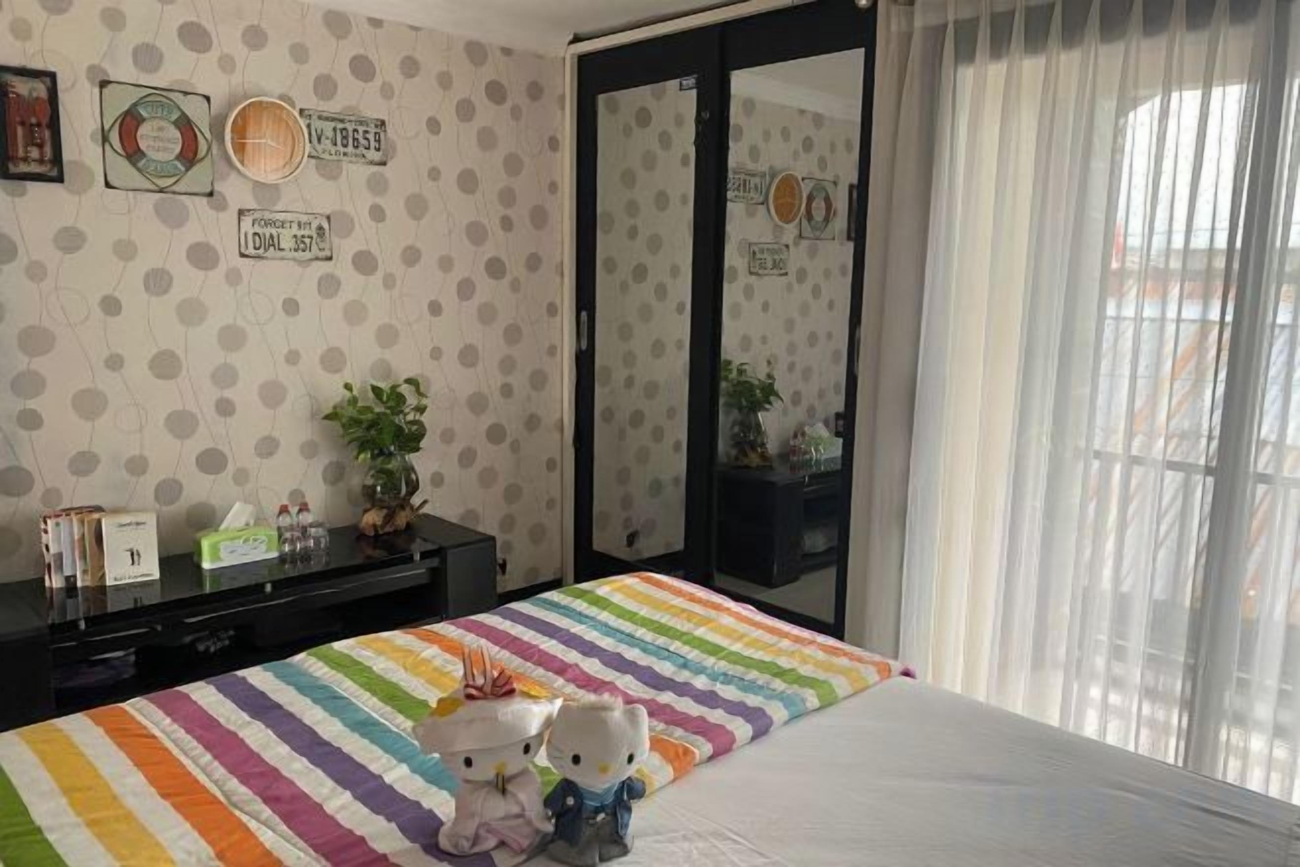 A bedroom with a striped bedspread, a mirror, and a plant on a dresser.