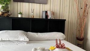 A neatly made bed with white linens, a black headboard, and decorative pillows. - MOZA HOUSE Wonosobo (Wonosobo)