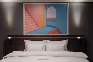 A bed with white bedding, a headboard, and a painting above it. - Urban HOTEL&PLAY (Seoul)