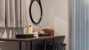 A modern room with a wooden desk, a chair, a small table, a sofa, a mirror, and a curtain. - Urban HOTEL&PLAY (Seoul)